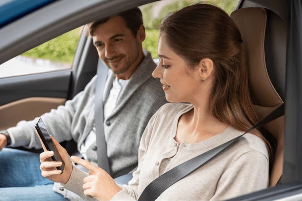 Duas pessoas, um homem e uma mulher com um celular na mão, dentro de um Chevrolet, representando o wi-fi nativo